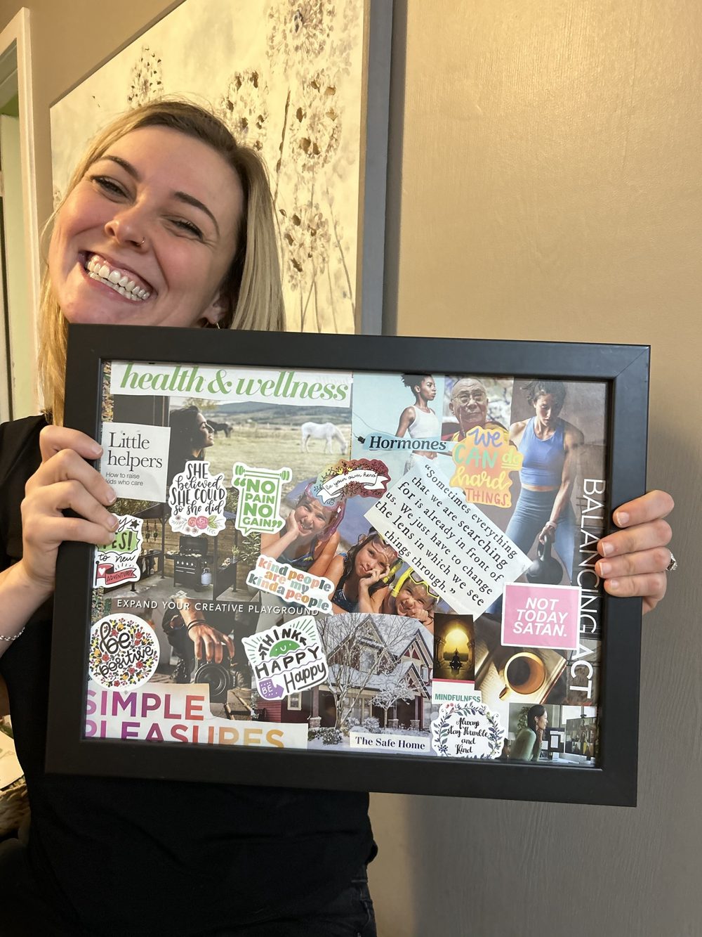 Smiling woman holding up her framed vision board